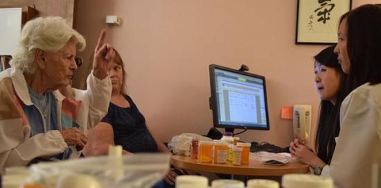 An elderly woman talking to research staff about her medication