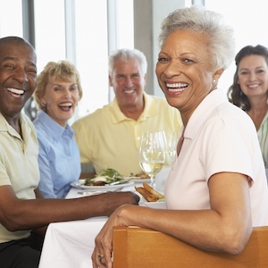 A group of elderly friends having lunch together at a restaurant and smiling